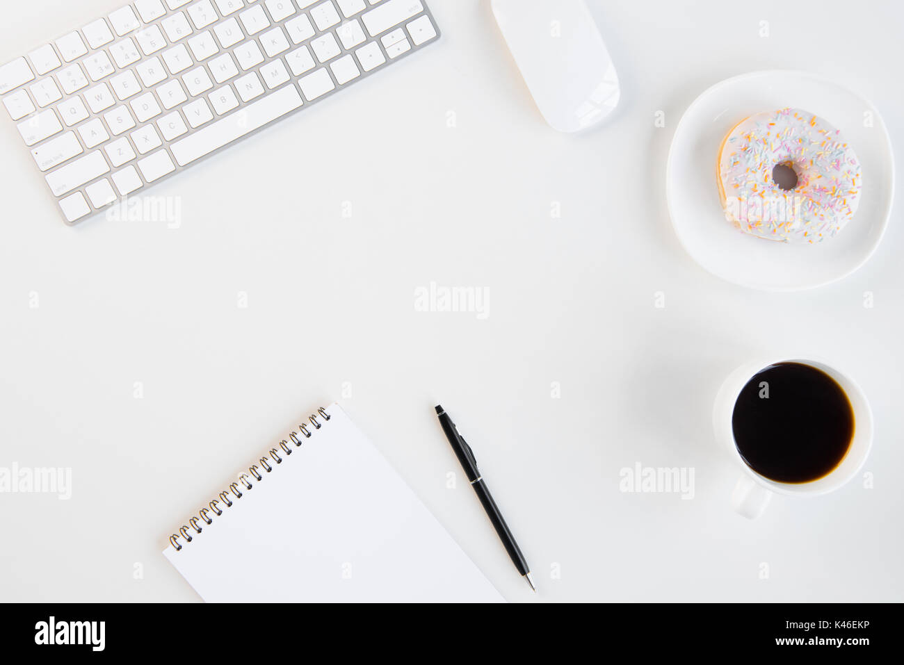 Vue de dessus du donut avec tasse de café vide, ordinateur portable avec stylo, clavier et souris de l'ordinateur sur le lieu de travail Banque D'Images