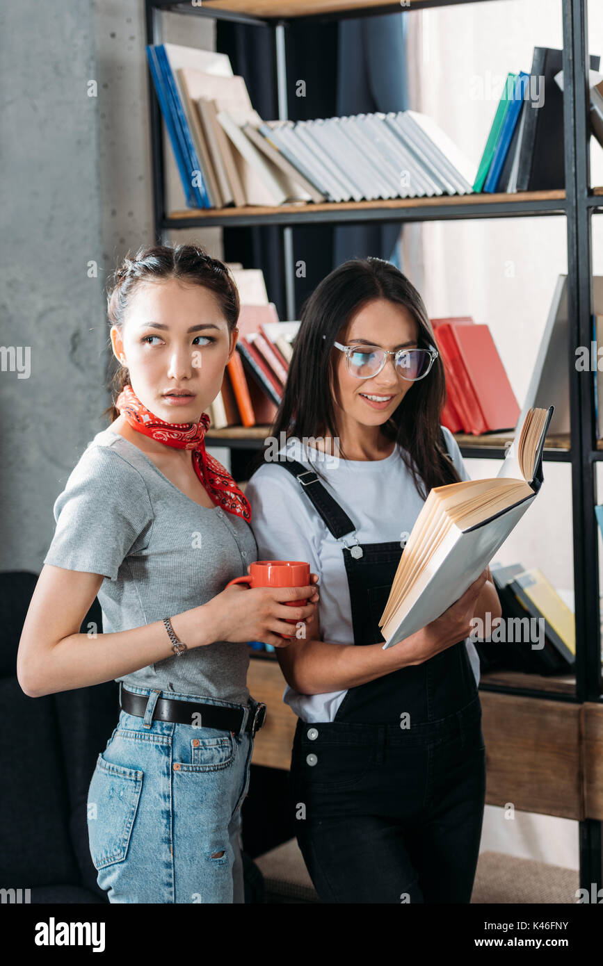 Les jeunes étudiants attrayant avec livre et d'étudier ensemble tasse et souriant Banque D'Images