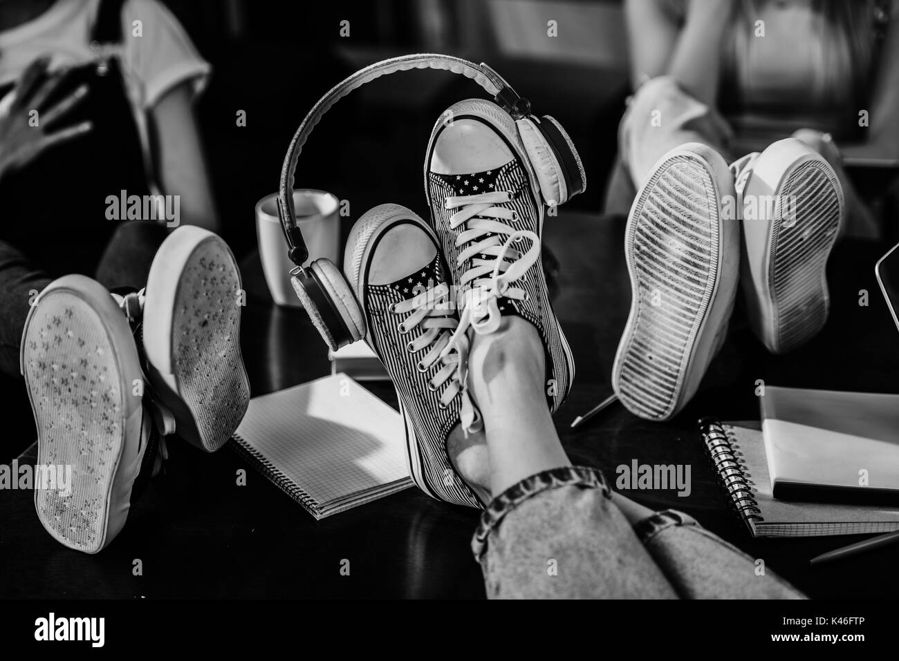 Close-up view of woman's pieds dans des chaussures élégantes avec des écouteurs sur la table en bois, photo en noir et blanc Banque D'Images