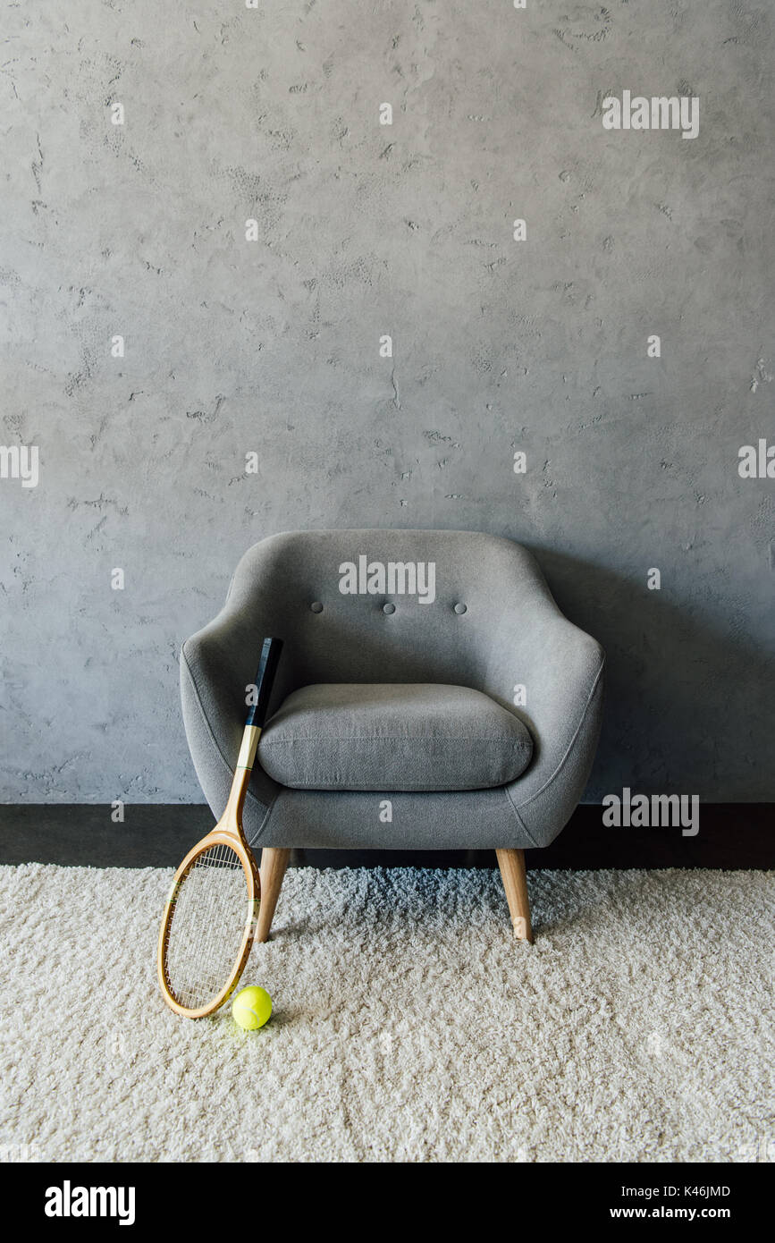 Raquette de tennis et la balle avec fauteuil gris à empty room Banque D'Images