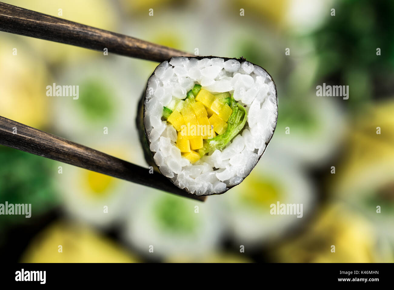 Maintenez le rouleau végétarien baguettes sur la plaque de sushi floue Banque D'Images