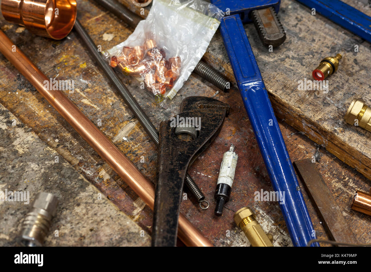 Rusty vieille paire de poignées plombiers réglable sur un établi avec différents raccords de plomberie Banque D'Images