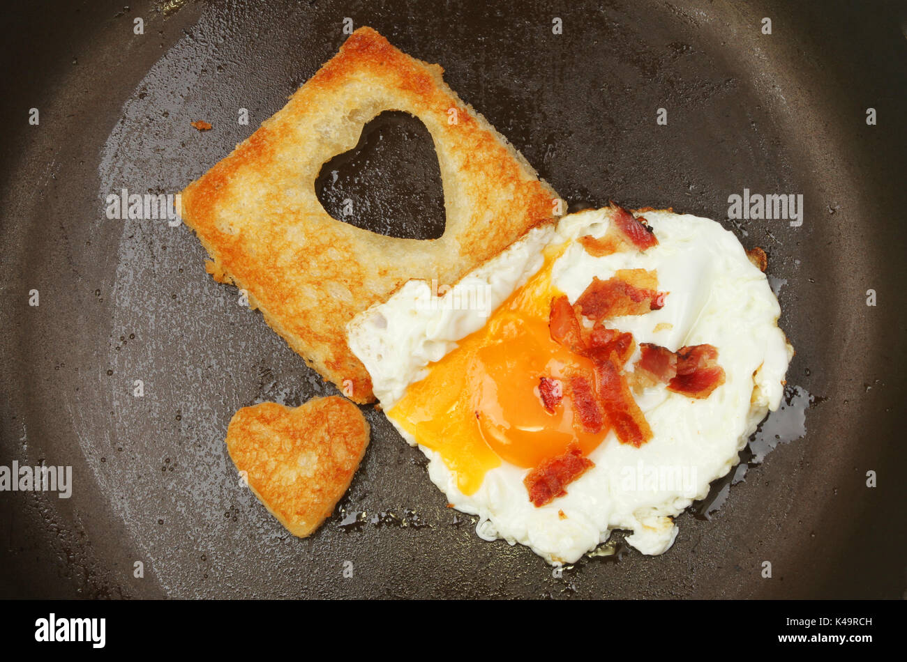 En forme de coeur pain frit avec un œuf frit et la pancetta dans une poêle Banque D'Images