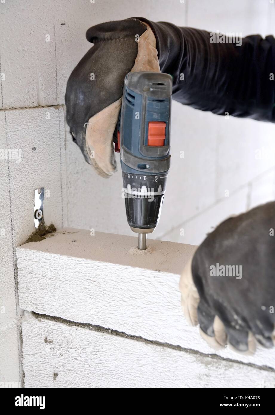 Le maçon à l'aide d'un tournevis batterie pour percer une vis dans un mur en béton blocs aérés. Banque D'Images