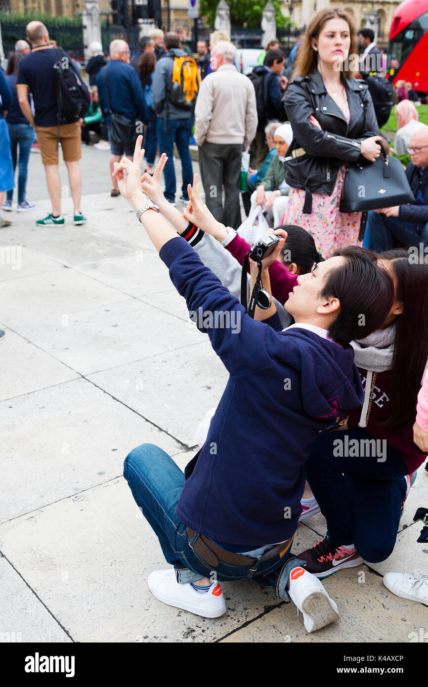 Londres, Royaume-Uni. Les touristes asiatiques s'arrêter pour prendre un en selfies Place du Parlement. Banque D'Images