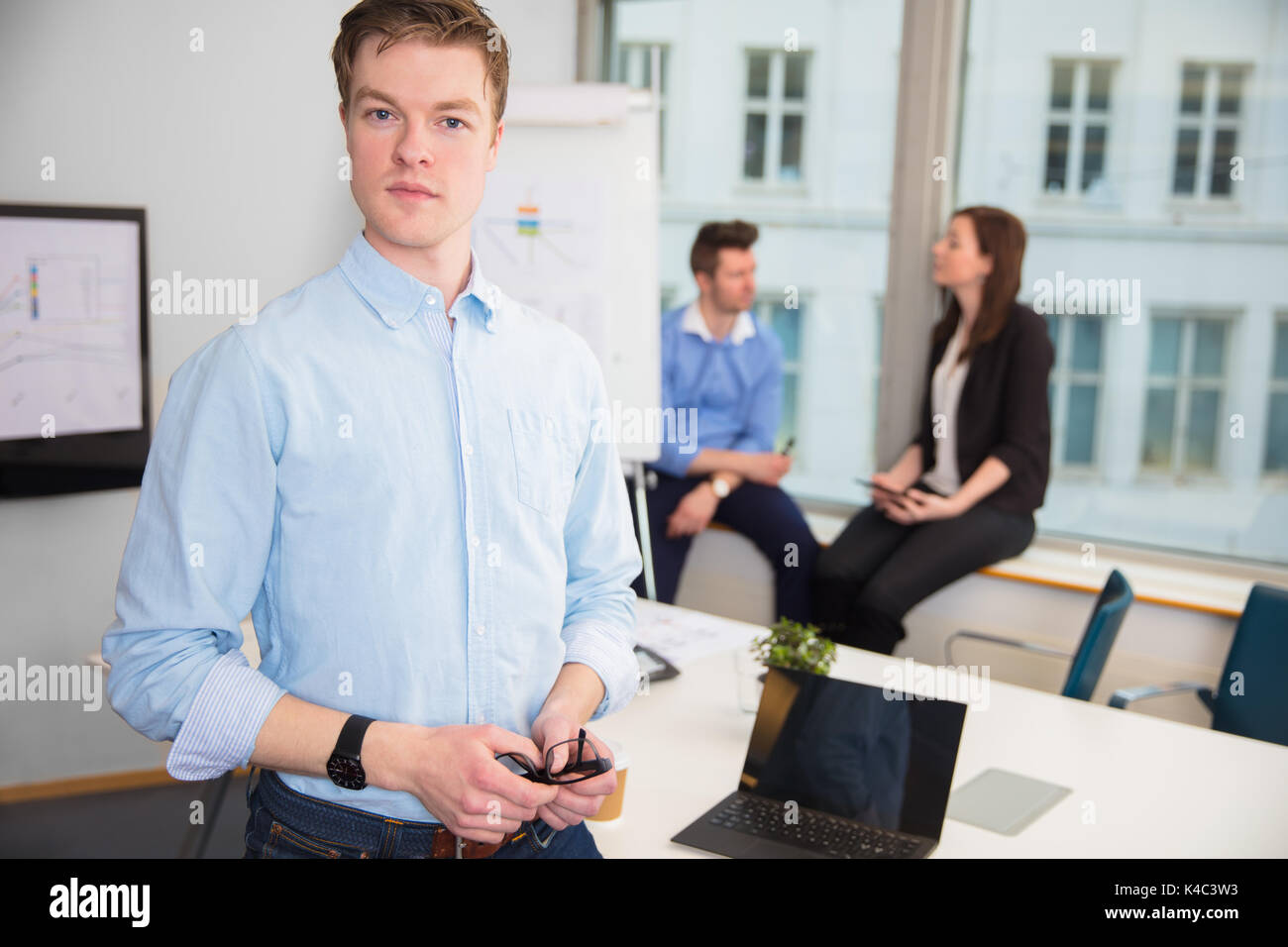 Businessman Standing alors que collègues assis sur le rebord de fenêtre Banque D'Images