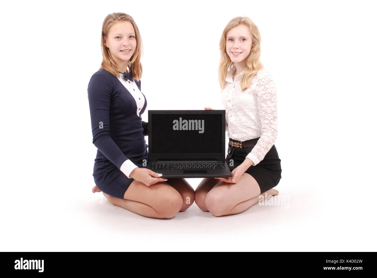 Deux jeunes filles à l'aide d'ordinateur portable isolé sur fond blanc Banque D'Images