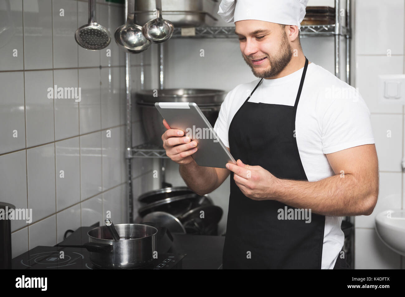 Portrait of smiling chef de la lecture sur tablette dans la cuisine Banque D'Images