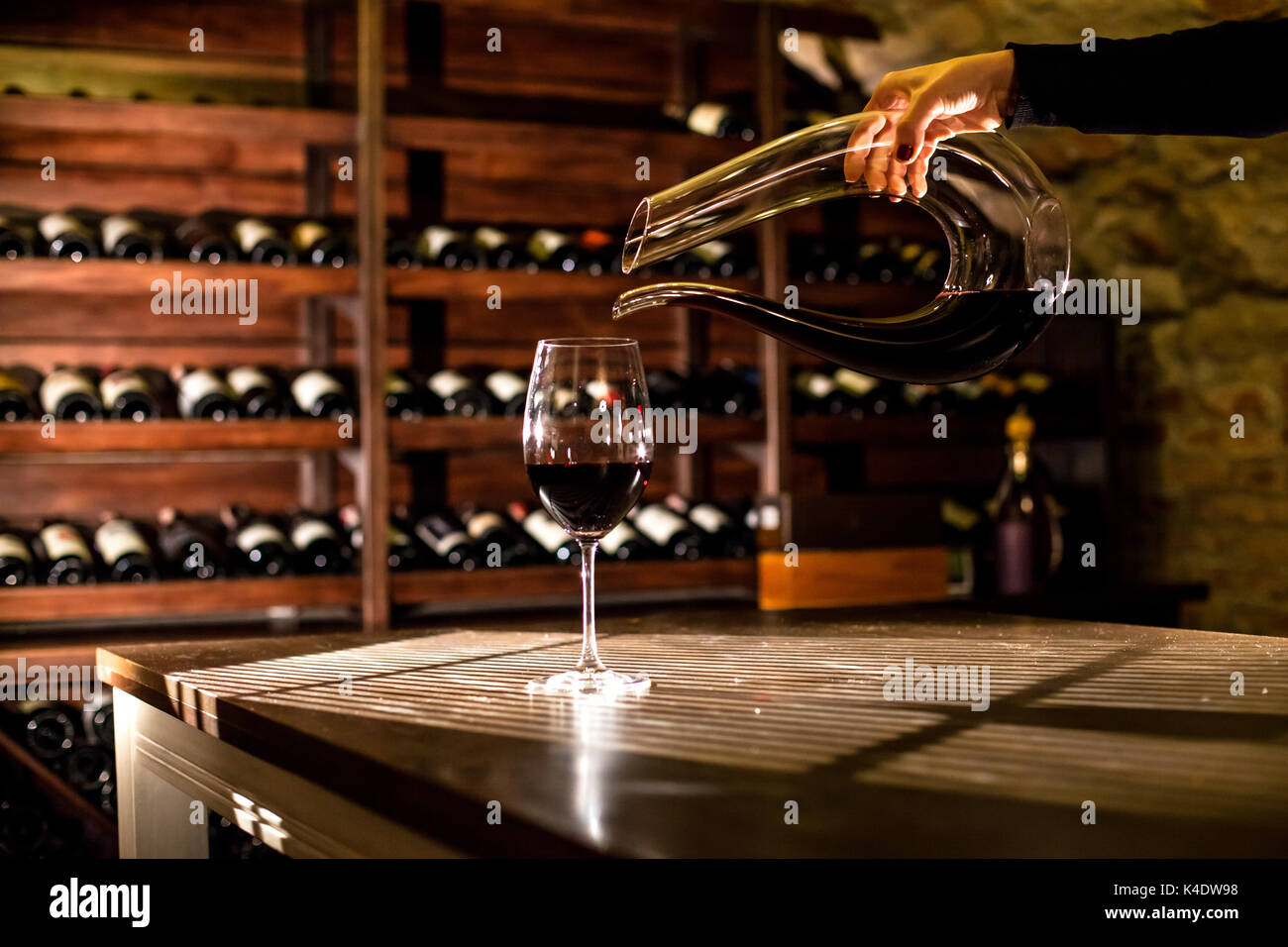 Main tenant une bouteille de vin. Verser le vin dans un verre. L'emplacement de la base de vin. Banque D'Images