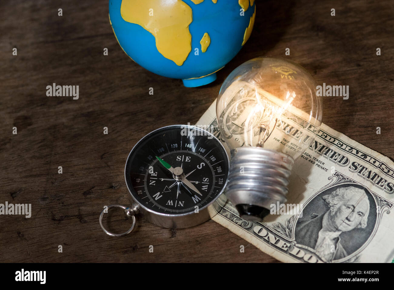 Compas de navigation, l'ampoule allumée, et un globe terrestre en plus d'un projet de loi d'un dollar US, avec un fond de bois Banque D'Images