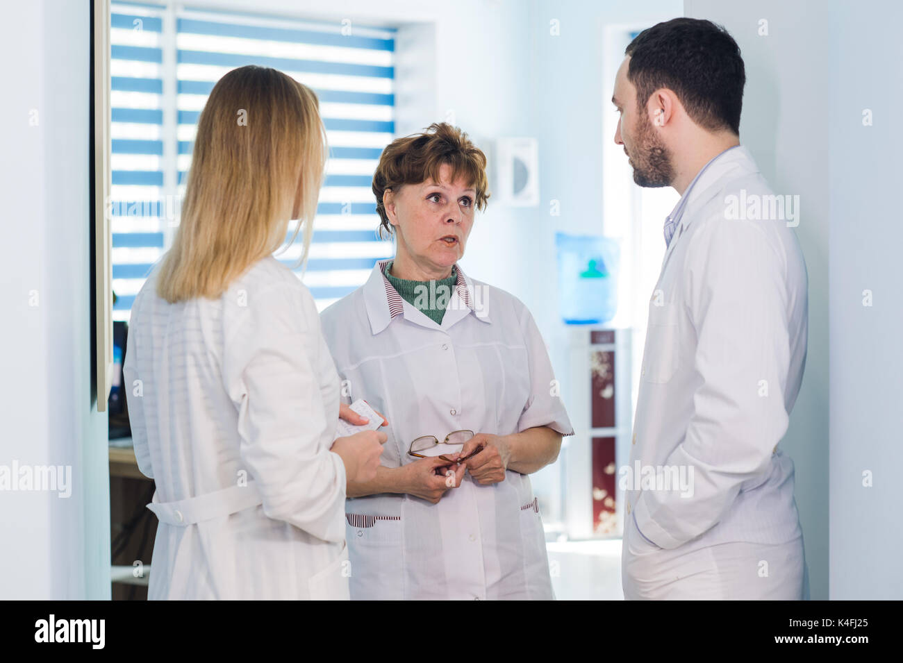 Mature doctor discuter avec les infirmières dans un couloir l'hôpital. Discuter de l'état du patient médecin avec son personnel médical après l'opération Banque D'Images