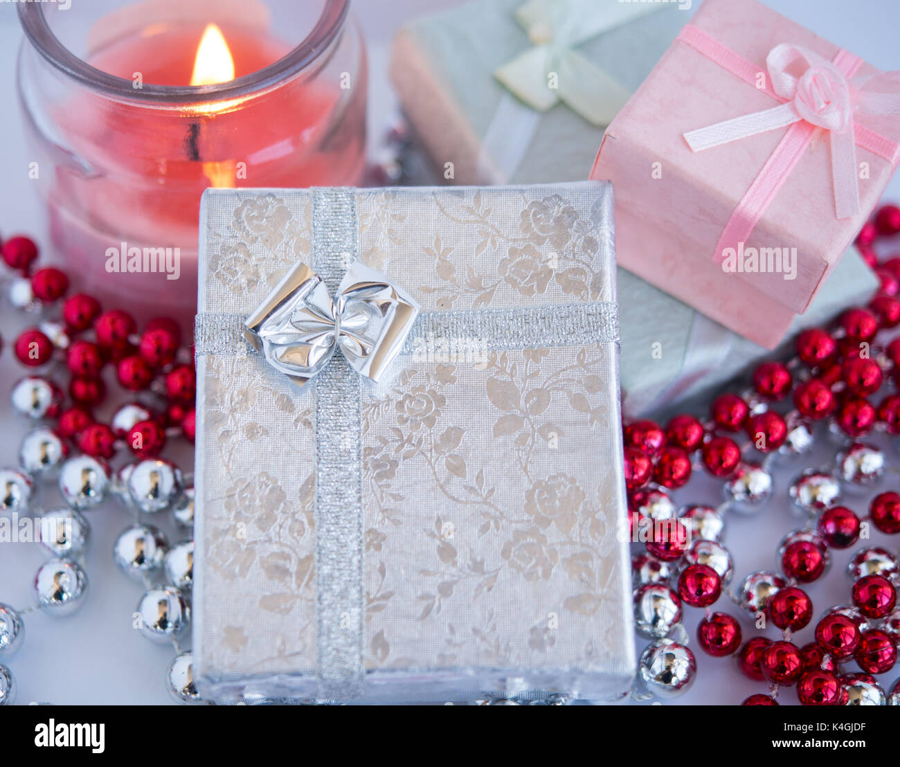 Les petites boîtes cadeau magnifique avec une bougie décorée par des perles sur un fond blanc. Banque D'Images