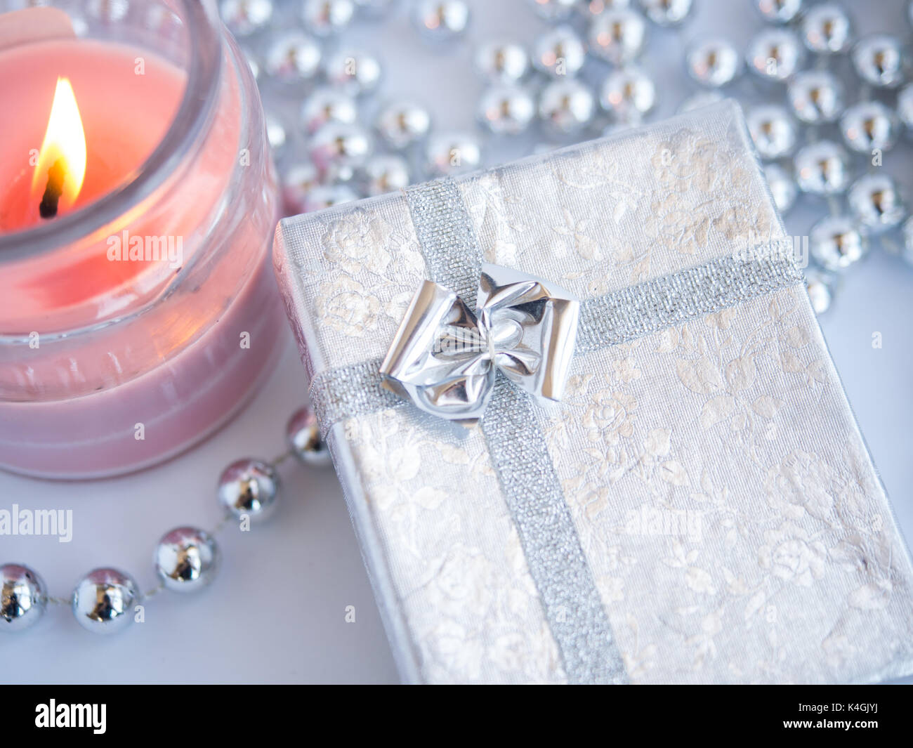 Belle petite boîte-cadeau avec une bougie décorée par des perles sur un fond blanc. Banque D'Images