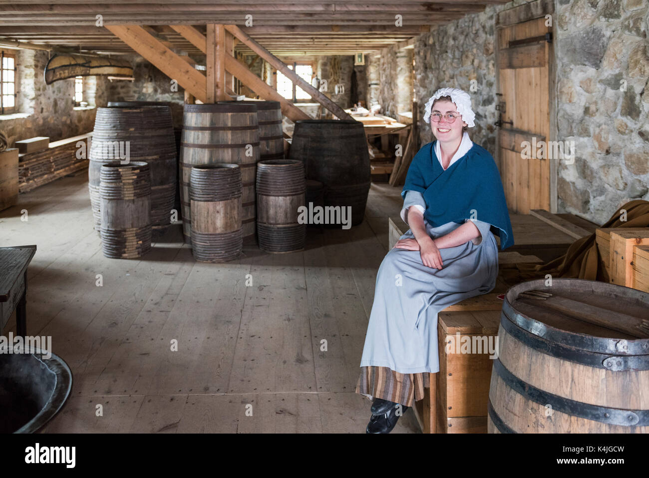 Femme en costume assis sur de barils pour le magasin du roi de la forteresse de Louisbourg, Louisbourg, île du Cap-Breton, Nouvelle-Écosse, Canada Banque D'Images