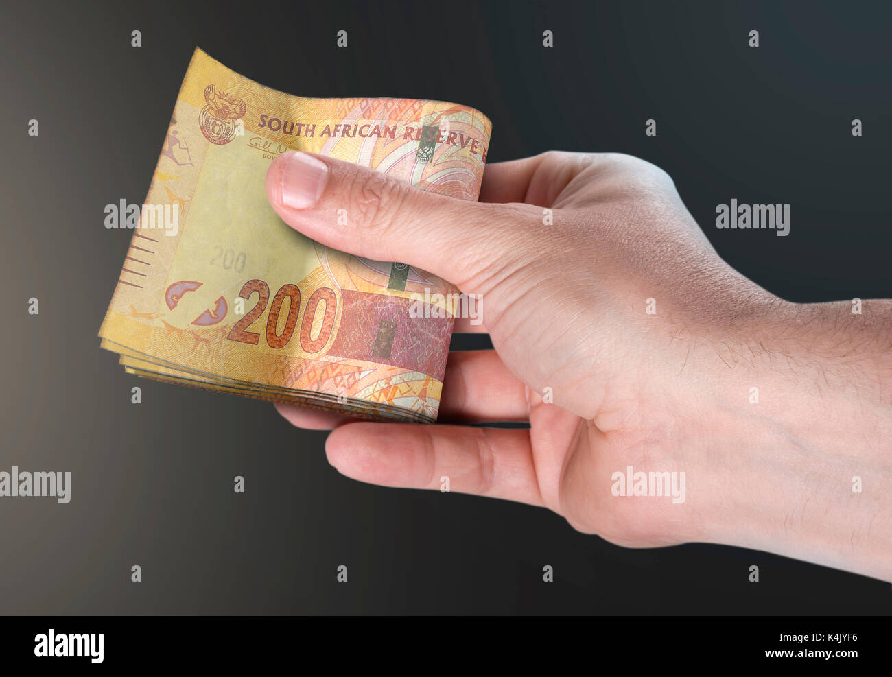 Un homme part remettre une liasse de rand sud africain pliée bank notes sur un fond isolé Banque D'Images