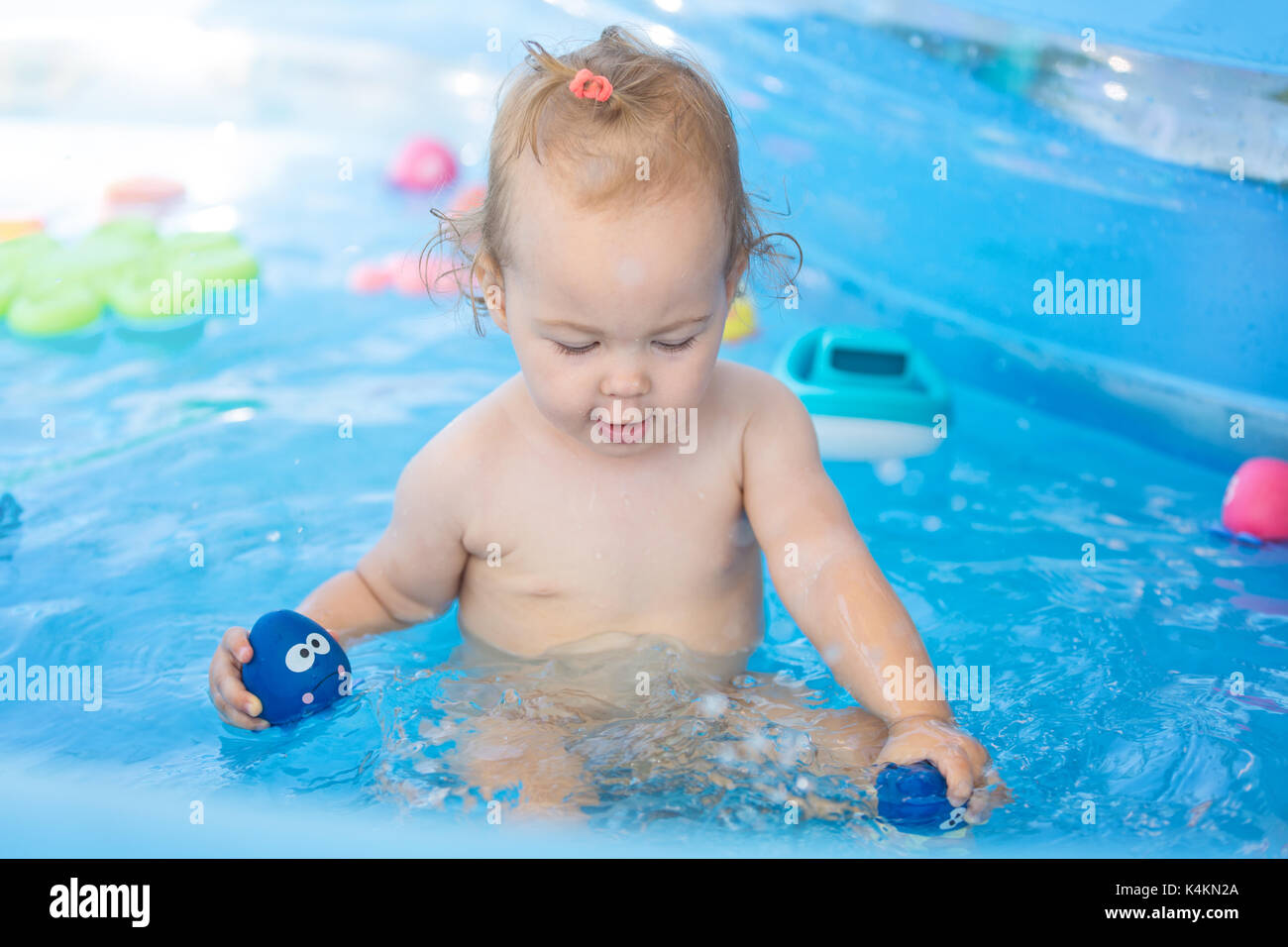 Seize mois bébé fille jouant dans la piscine en plastique avec ses jouets ;  bébé couvert de crème solaire ; soins de la petite enfance heureuse et  libre concept Photo Stock - Alamy