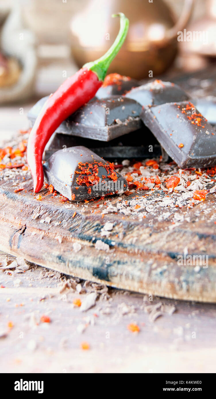 Morceaux de chocolat avec des piments sur une table en bois, d'épices, selective focus Banque D'Images