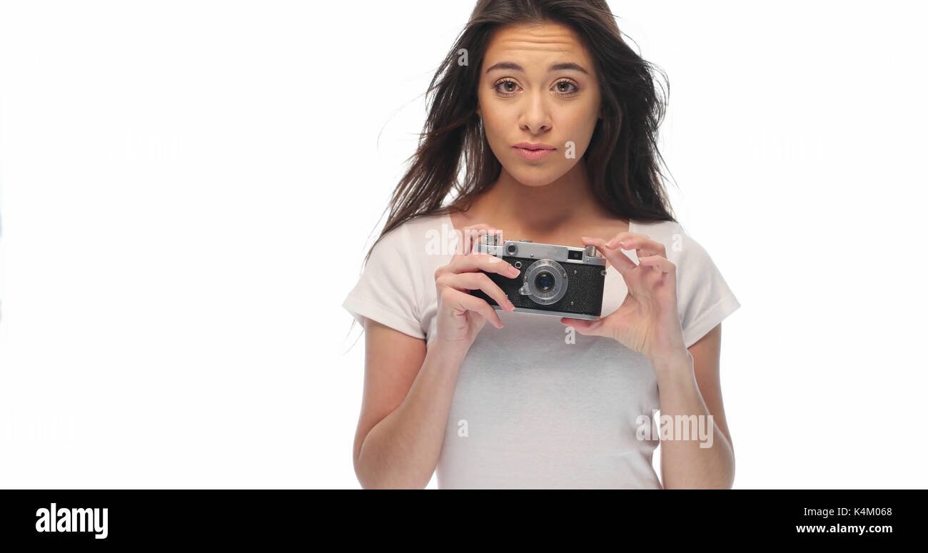 Closeup portrait of pretty young brunette woman in white t-shirt holding retro camera isolated over white background Banque D'Images