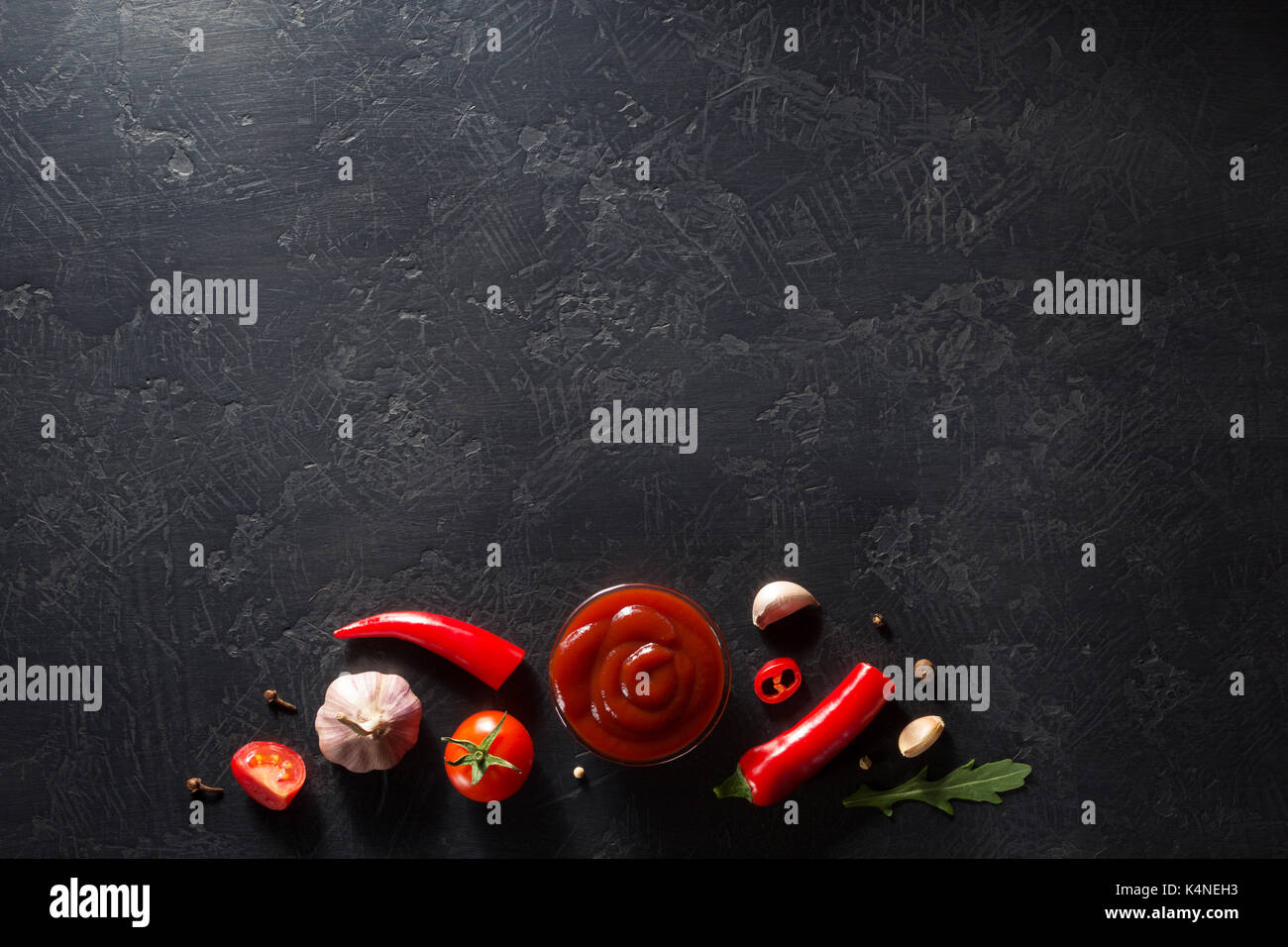 La sauce tomate dans un bol et jar sur fond noir texture Banque D'Images