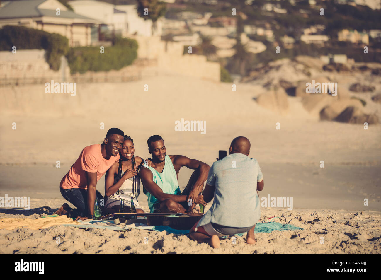 Jeune homme prend une photo de ses amis sur le bord de mer. Groupe d'amis sur la plage à prendre des photos. Banque D'Images