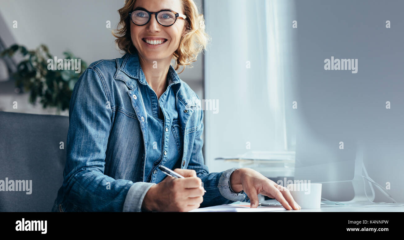 Portrait femme travaillant à son bureau en bureau. Femme à la direction de là et souriant. Banque D'Images