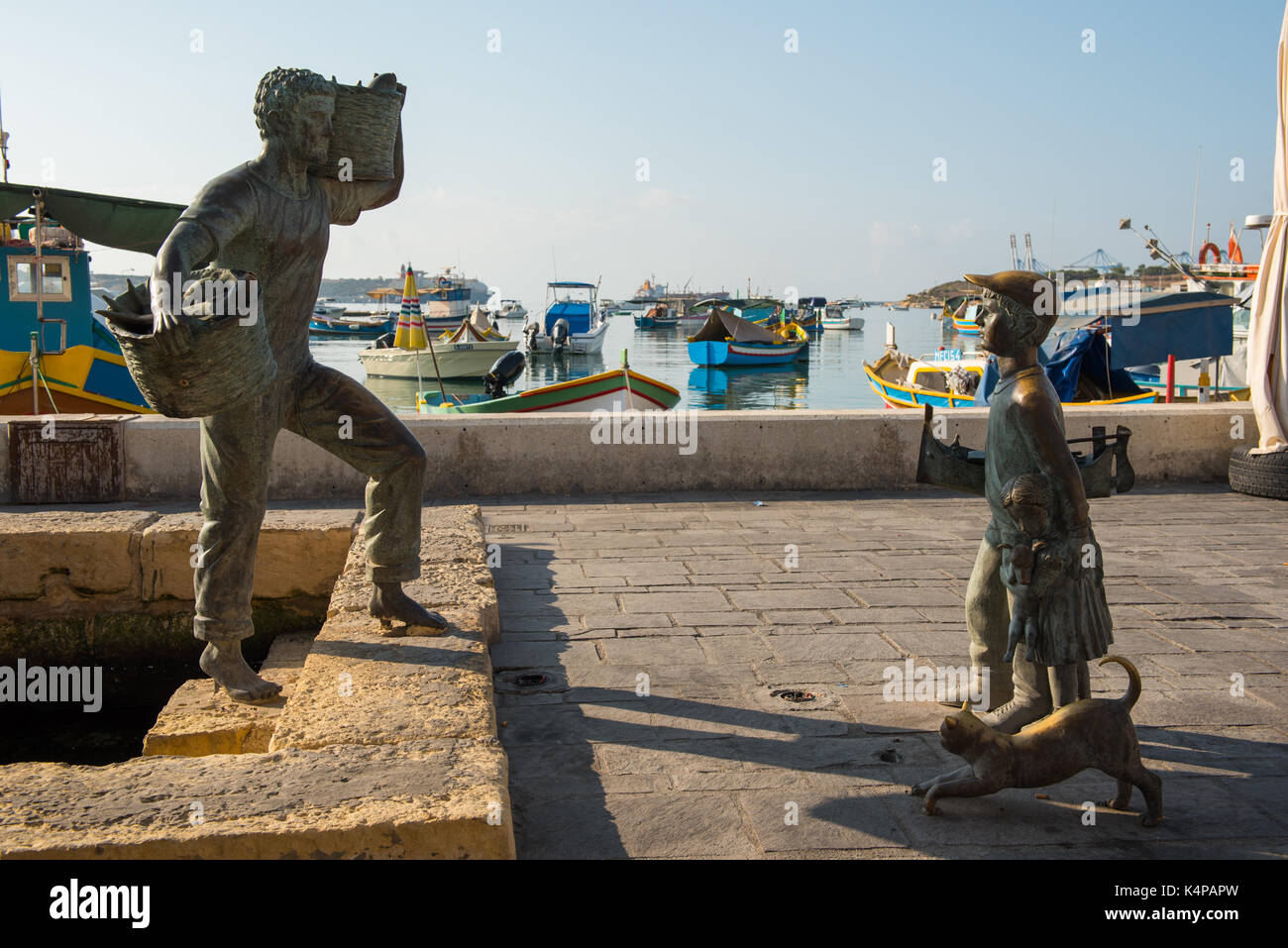 Marsaxlokk, Malte - 23 août 2017 : statue en bronze représentant un pêcheur et un jeune garçon avec un chat dans le port de Marsaxlokk bay dans l'île de Malte Banque D'Images