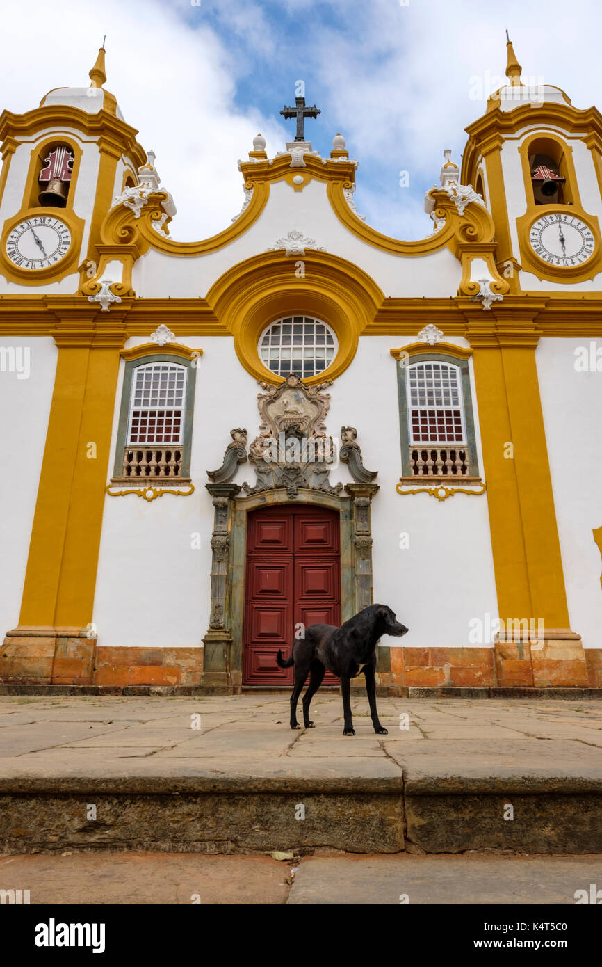 Chien Noir en face de l'église Matriz de Santo Antonio, le plus ancien et le principal temple catholique de Tiradentes, Minas Gerais, Brésil. Banque D'Images