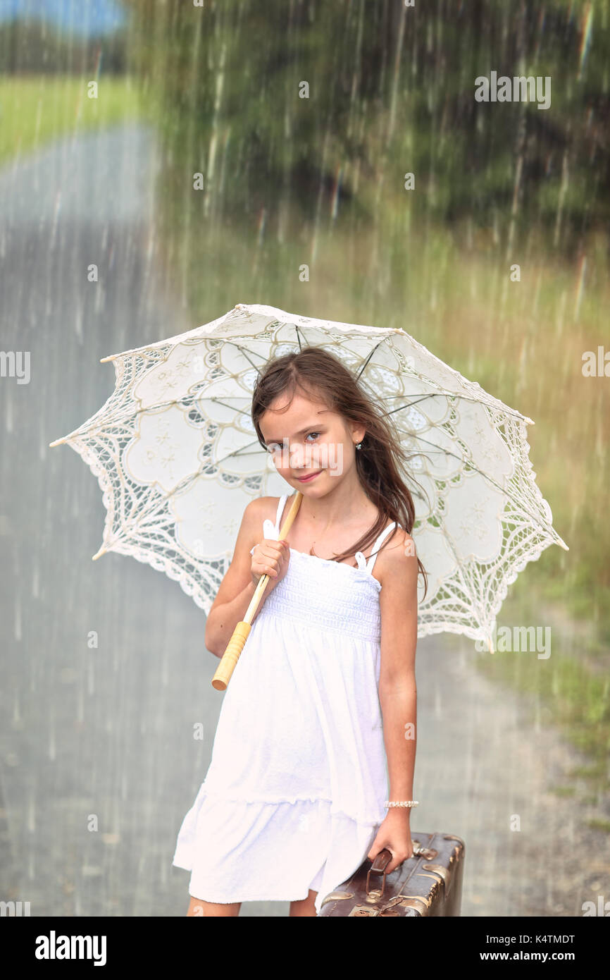 De l'été Voyage aventure - fille avec valise et parapluie sur un jour d'été pluvieux Banque D'Images