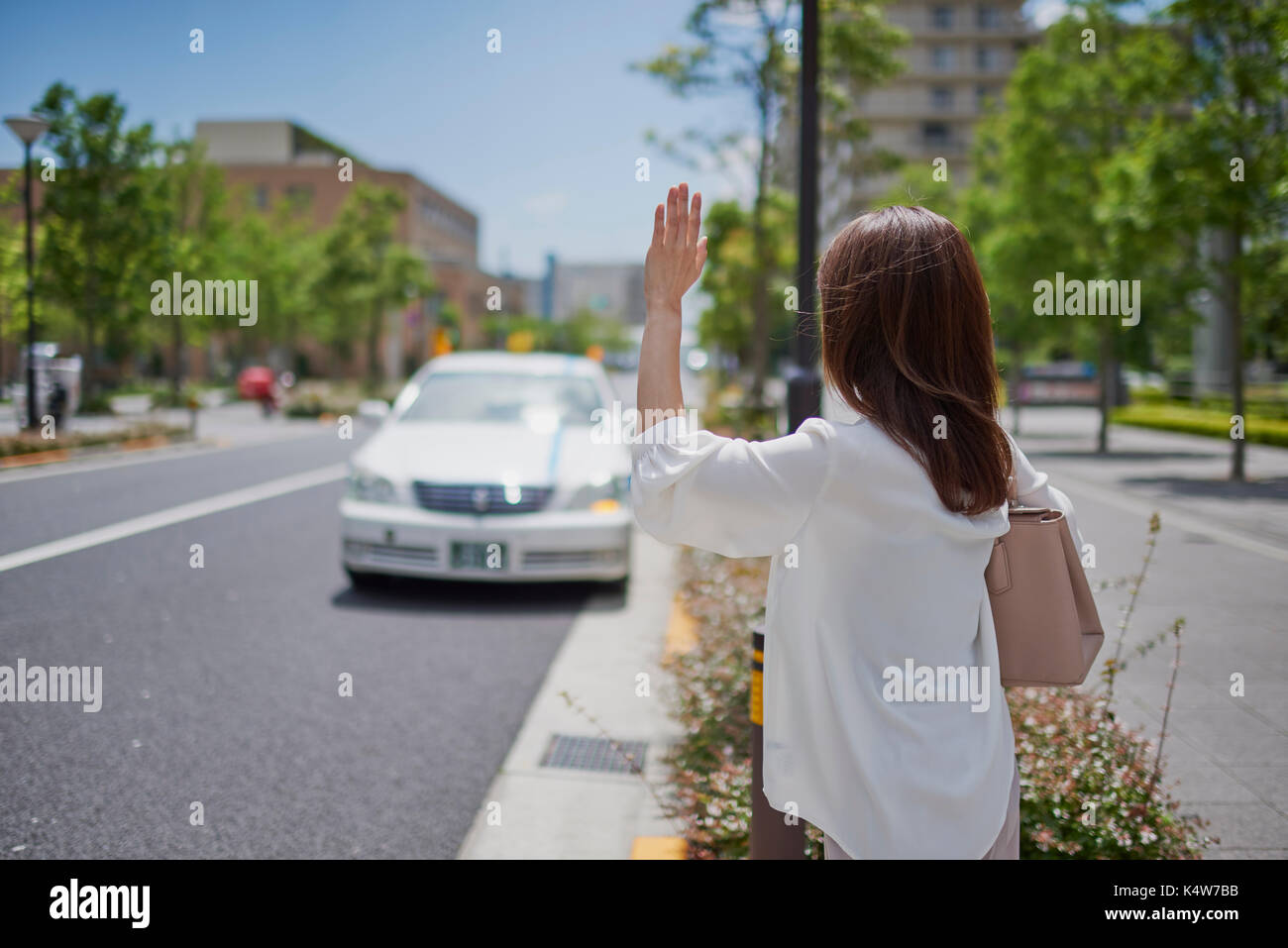 Jeune japonaise appelant un taxi Tokyo, Japan Banque D'Images