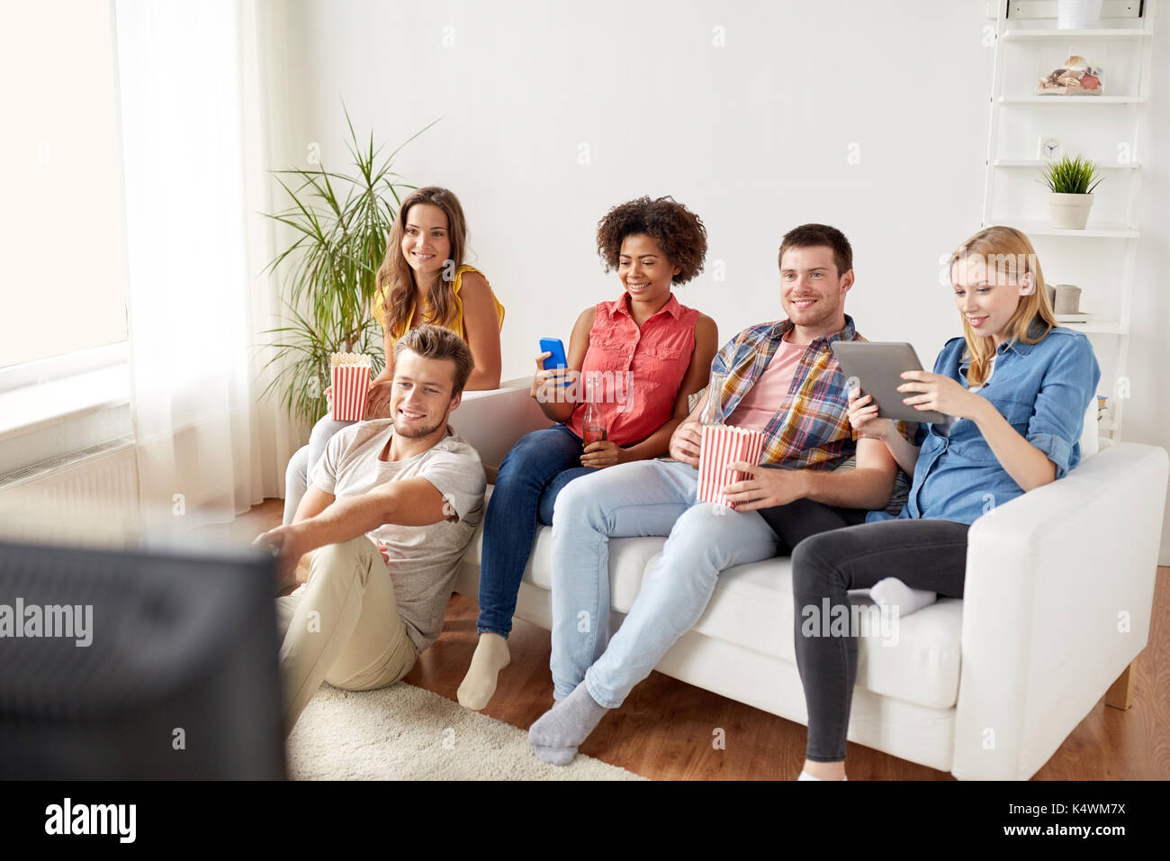 Les amis de gadgets et de la bière en regardant la télé à la maison Banque D'Images