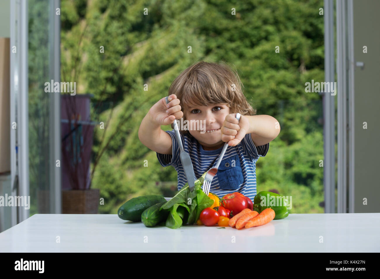 Adorable petit garçon assis à la table de légumes emballés par repas, bonnes ou mauvaises habitudes alimentaires, la nutrition et la saine alimentation concept Banque D'Images