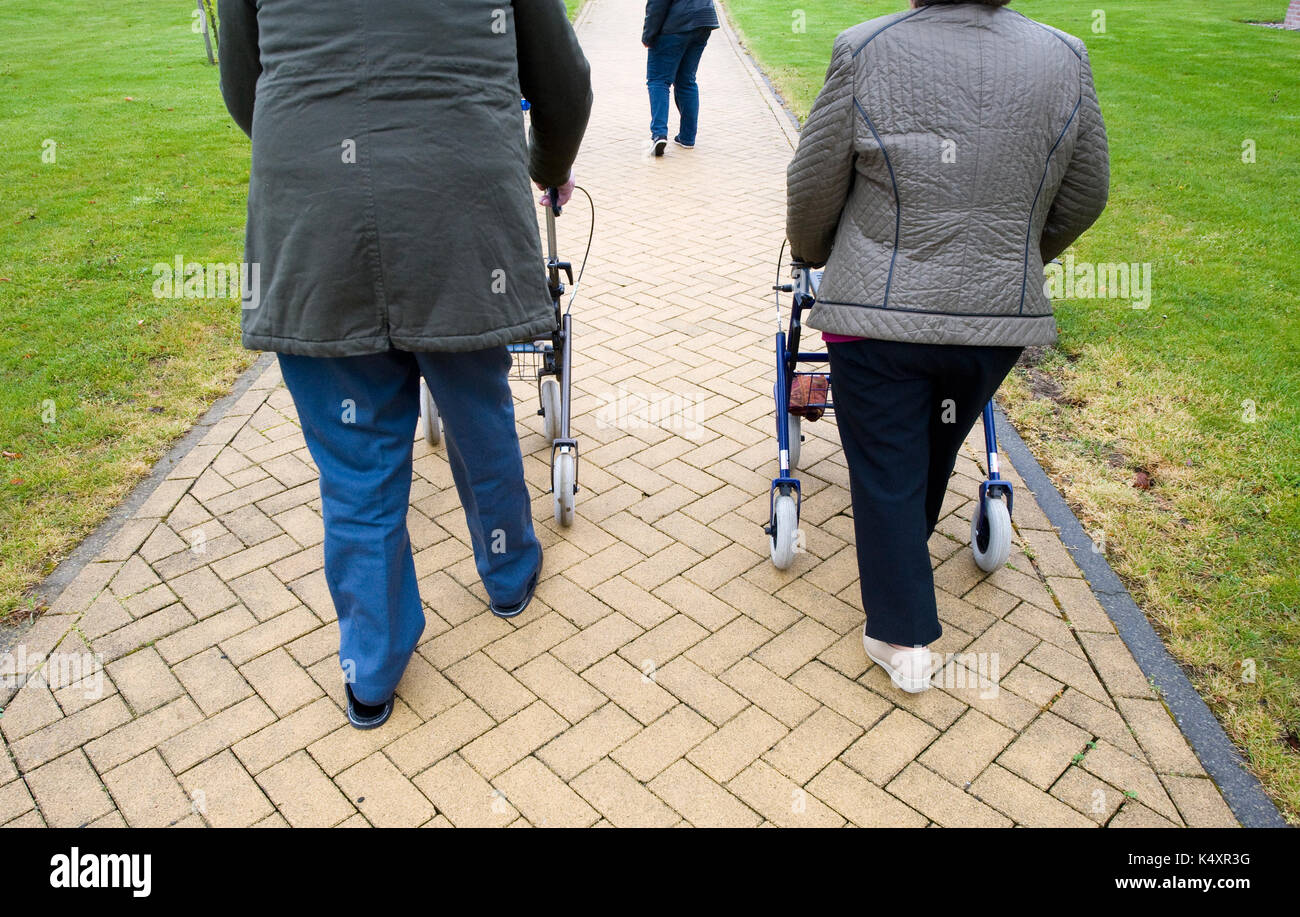 Un couple de personnes âgées à marcher derrière leurs cadres de marche Banque D'Images