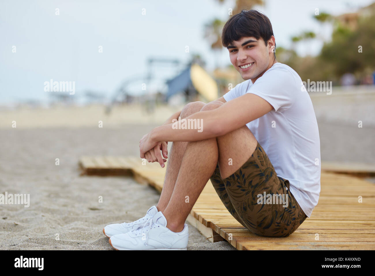 Portrait of young man sitting on beach smiling Banque D'Images