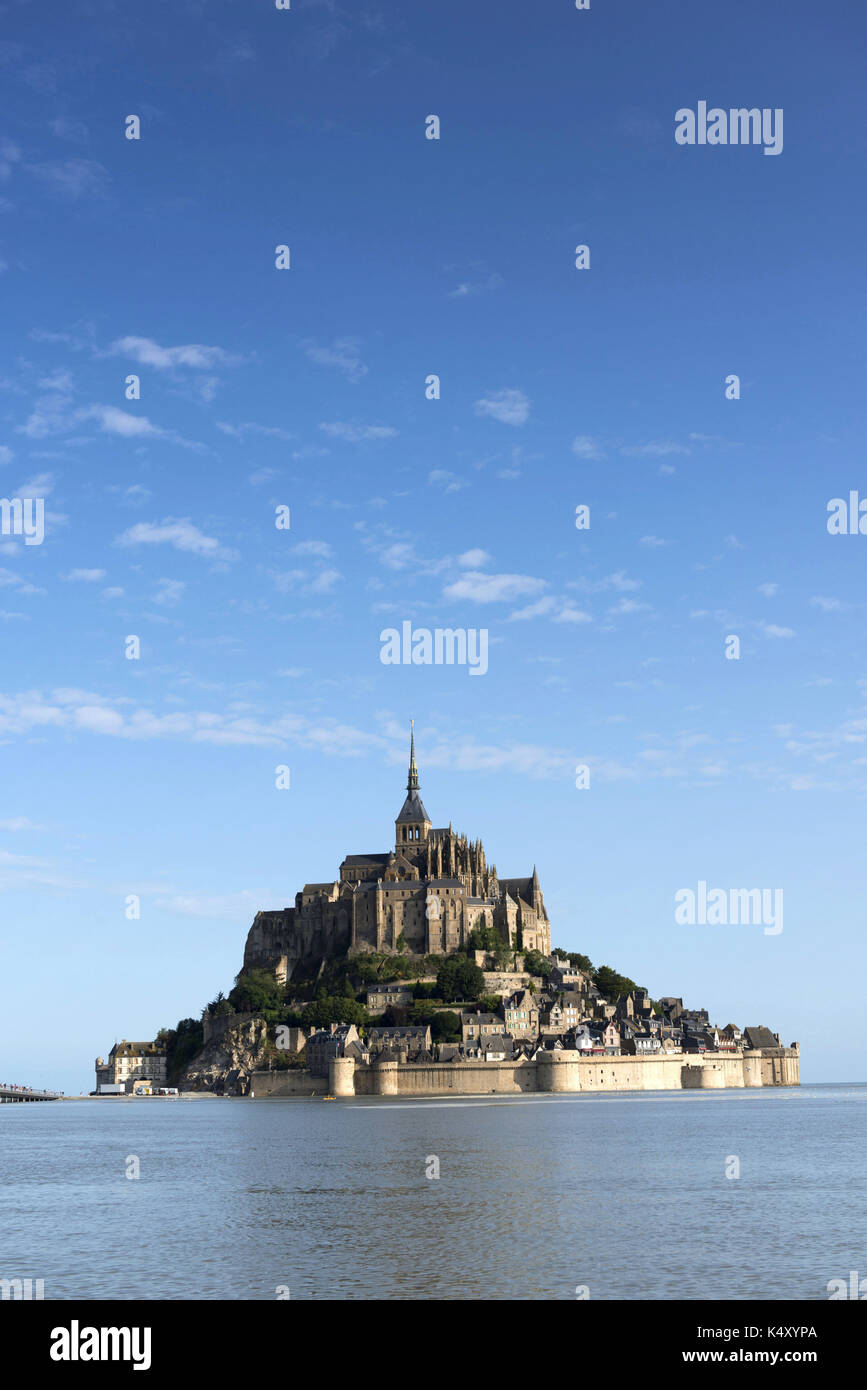 Le Mont-Saint-Michel et l'abbaye entourée d'eau. Ciel bleu Banque D'Images