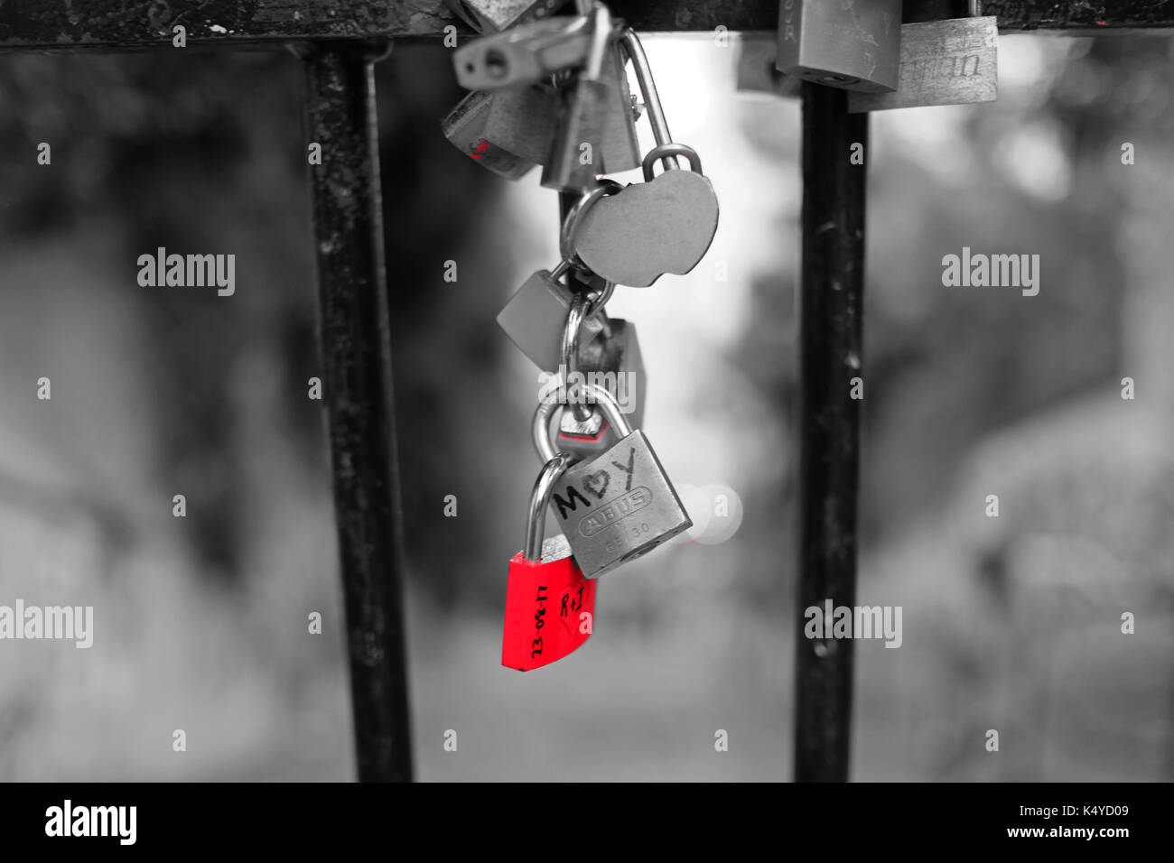 Love locks attachées à des garde-corps par des couples dans l'amour, à Montmartre, Paris, l'un est rouge sur un fond noir et blanc Banque D'Images