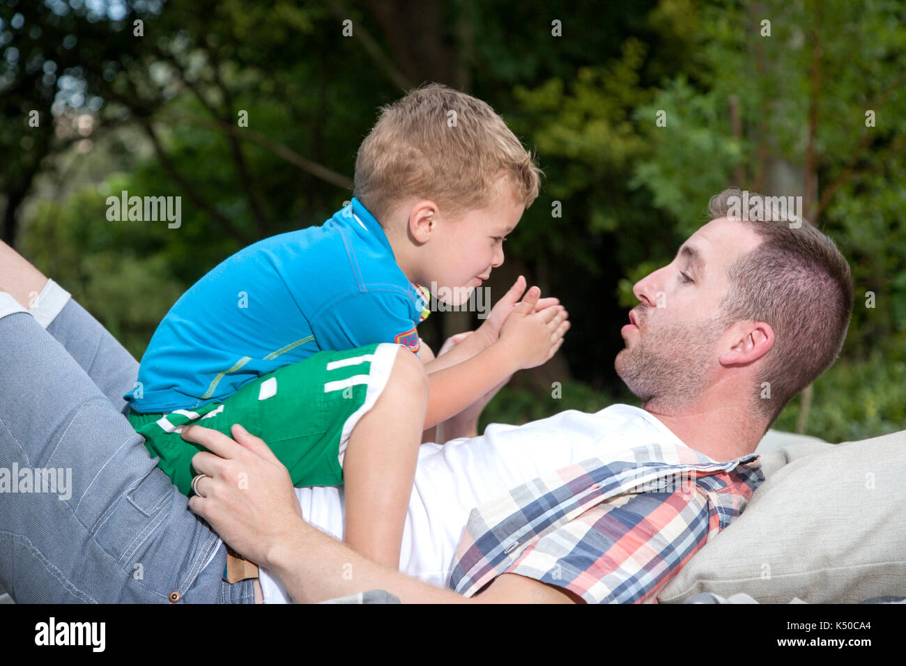 Fils assis sur l'estomac de ses pères Banque D'Images
