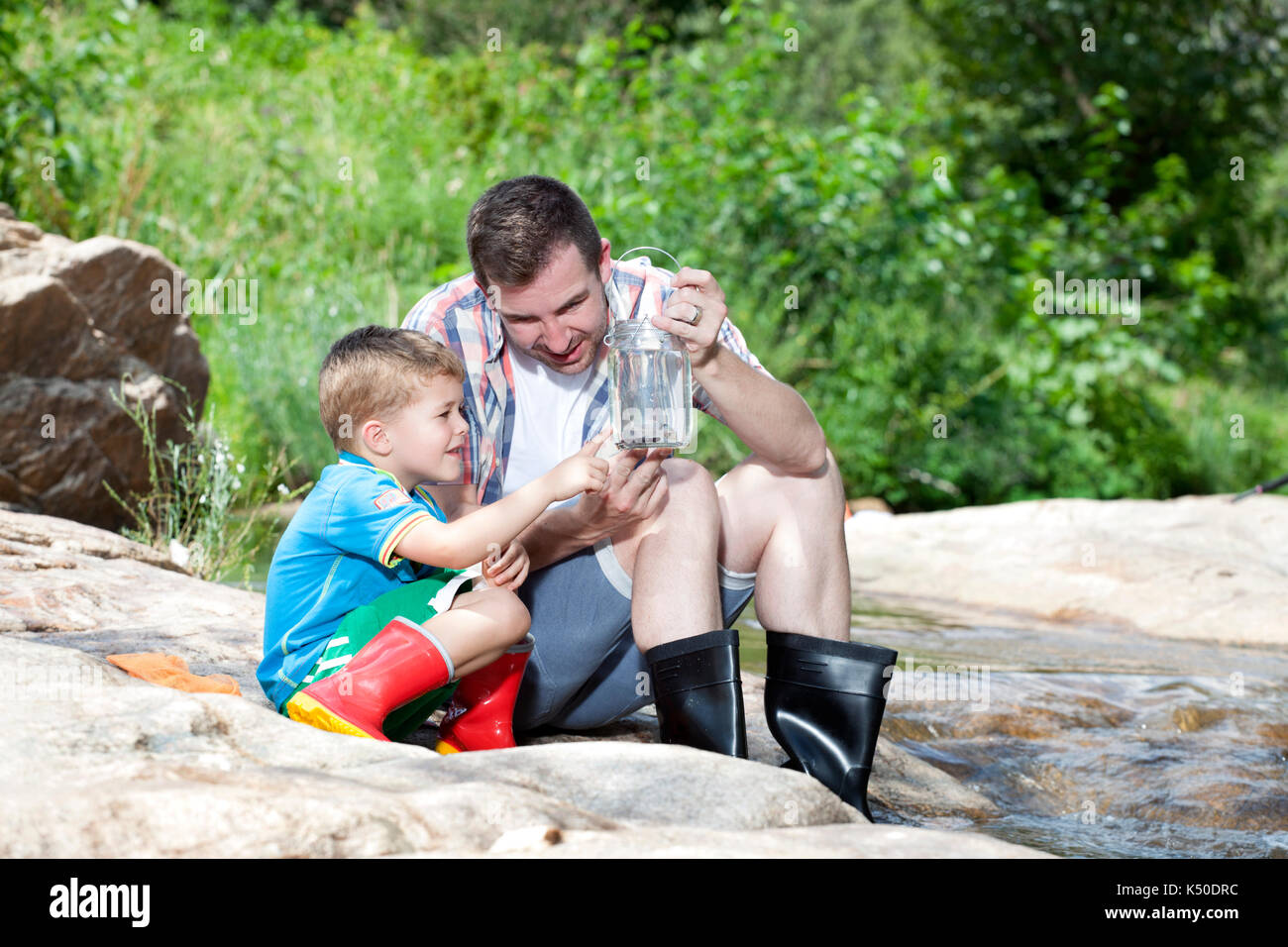 Père montrant son fils un poisson dans une bouteille Banque D'Images