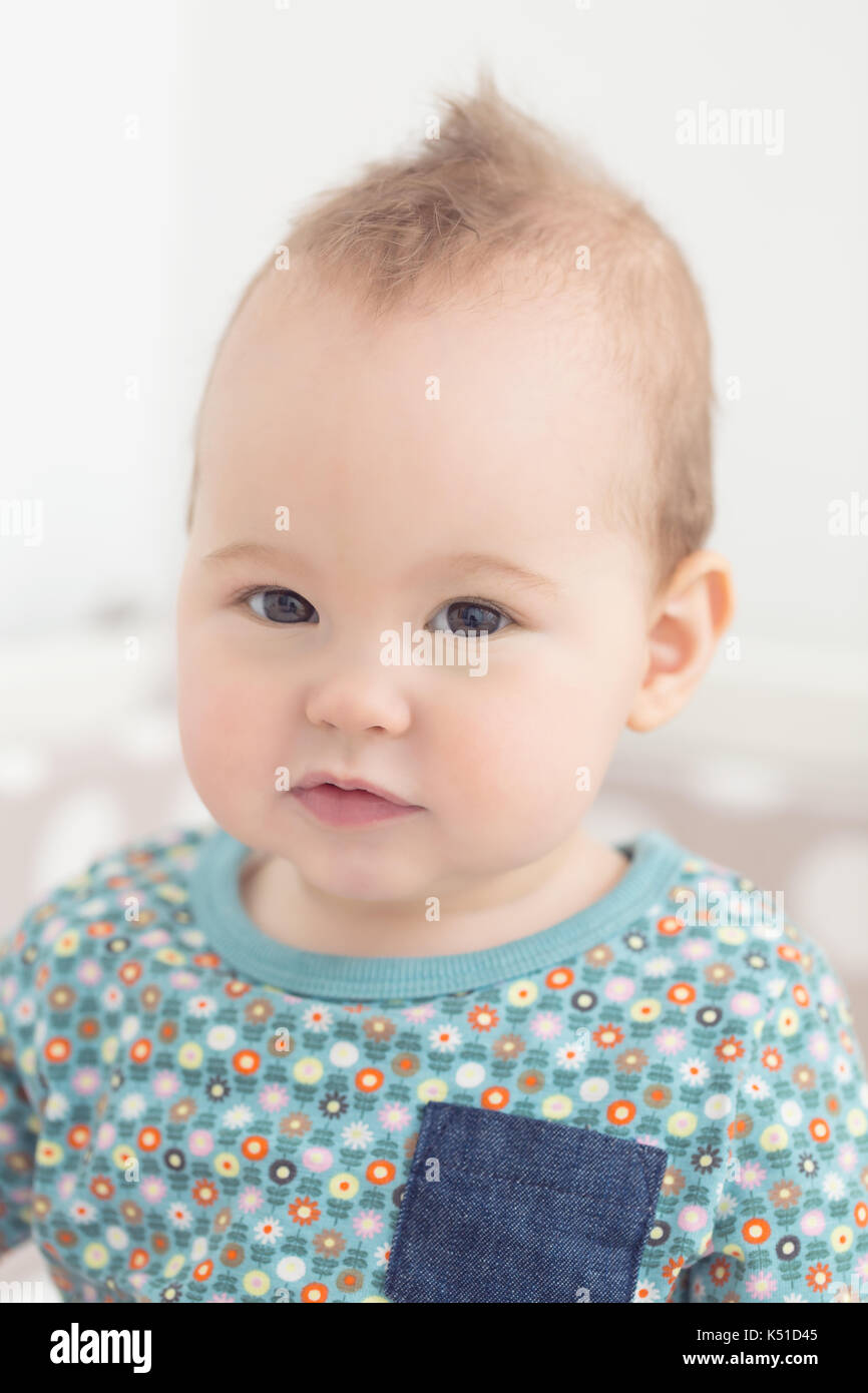 8 mois bébé fille regardant la caméra, avec sa bouche grande ouverte, assis dans son lit Banque D'Images