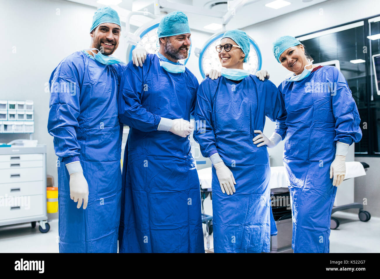 Portrait de l'équipe de chirurgien en salle d'opération permanent. Heureux travailleurs médicaux en chirurgie, dans l'uniforme dans l'exploitation du théâtre. Banque D'Images