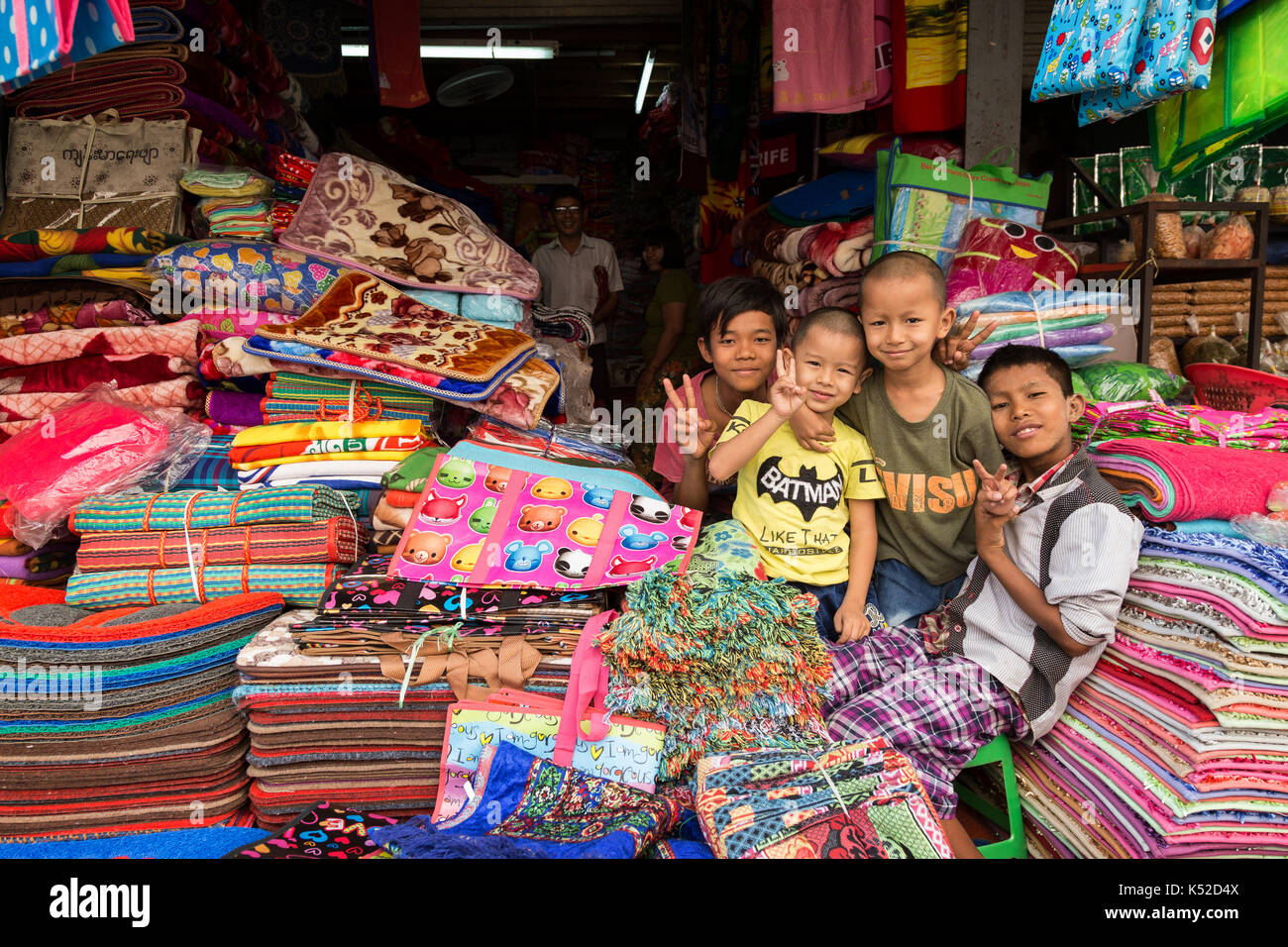 Quatre jeunes garçons heureux à un décrochage des marchandises à la zegyo (également connu sous le nom de zay cho) marché à Mandalay, Myanmar (Birmanie). Banque D'Images