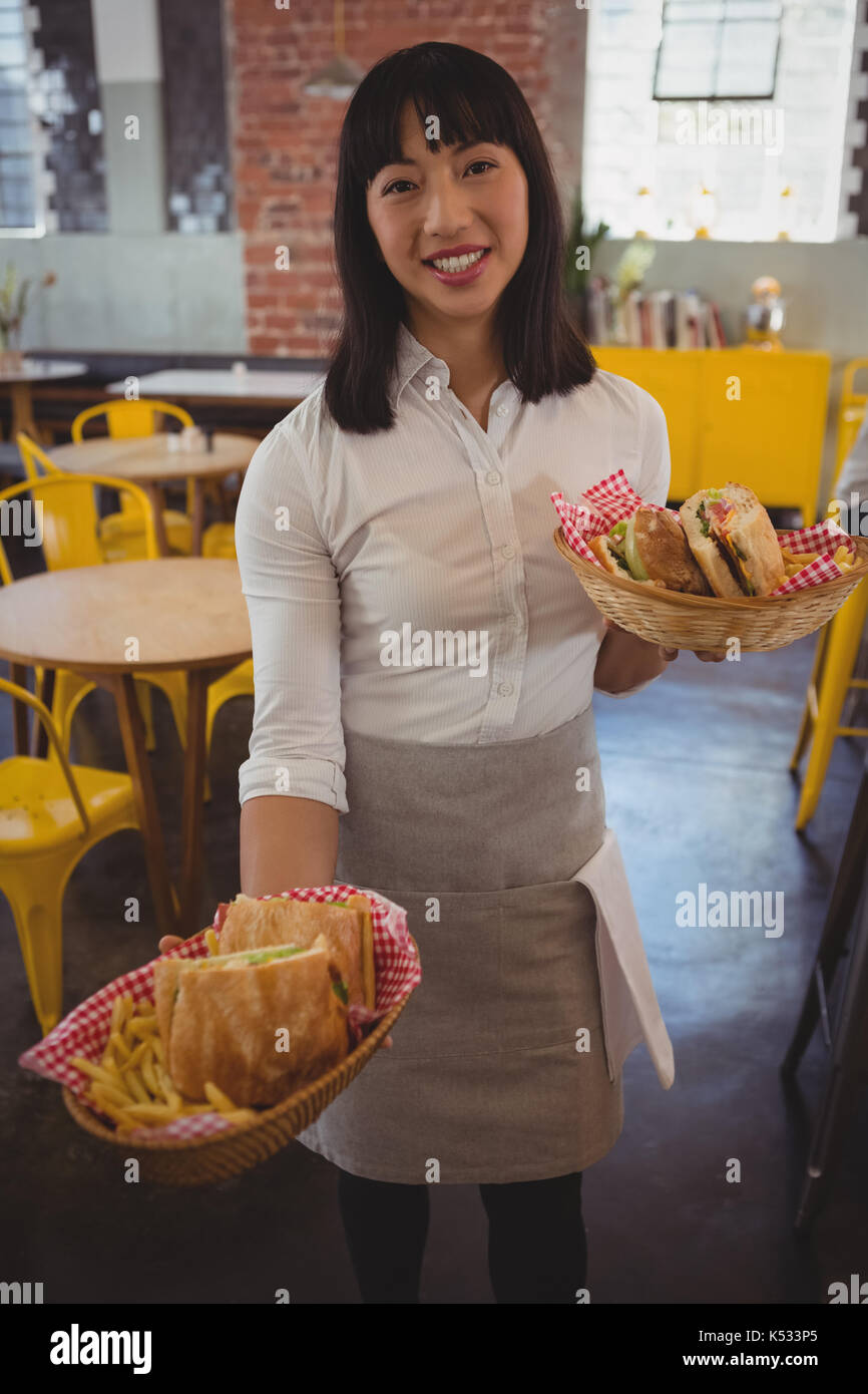 Portrait of young waitress holding paniers avec des sandwichs au cafe Banque D'Images