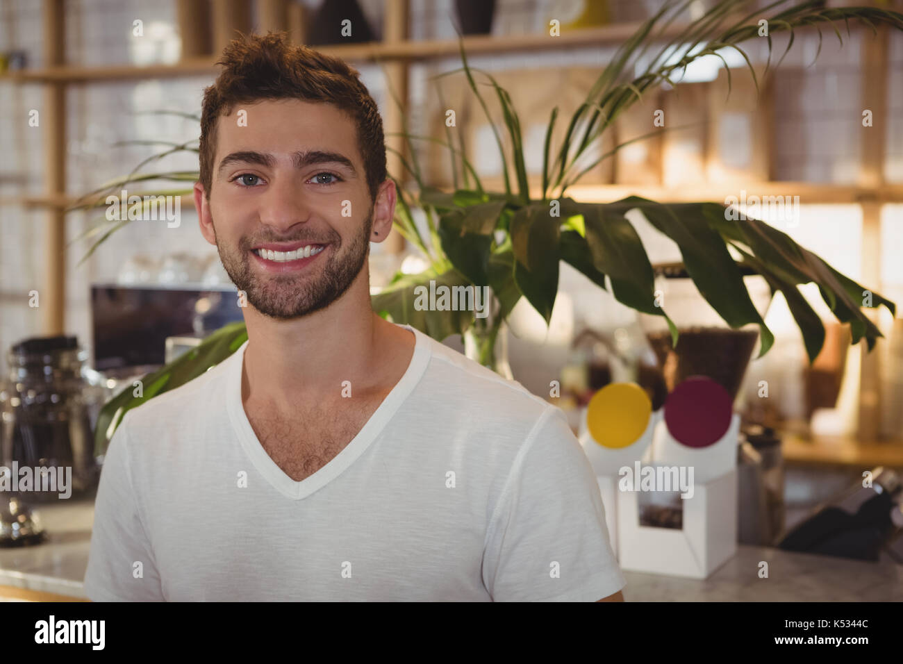 Portrait of smiling youngh man standing at cafe Banque D'Images
