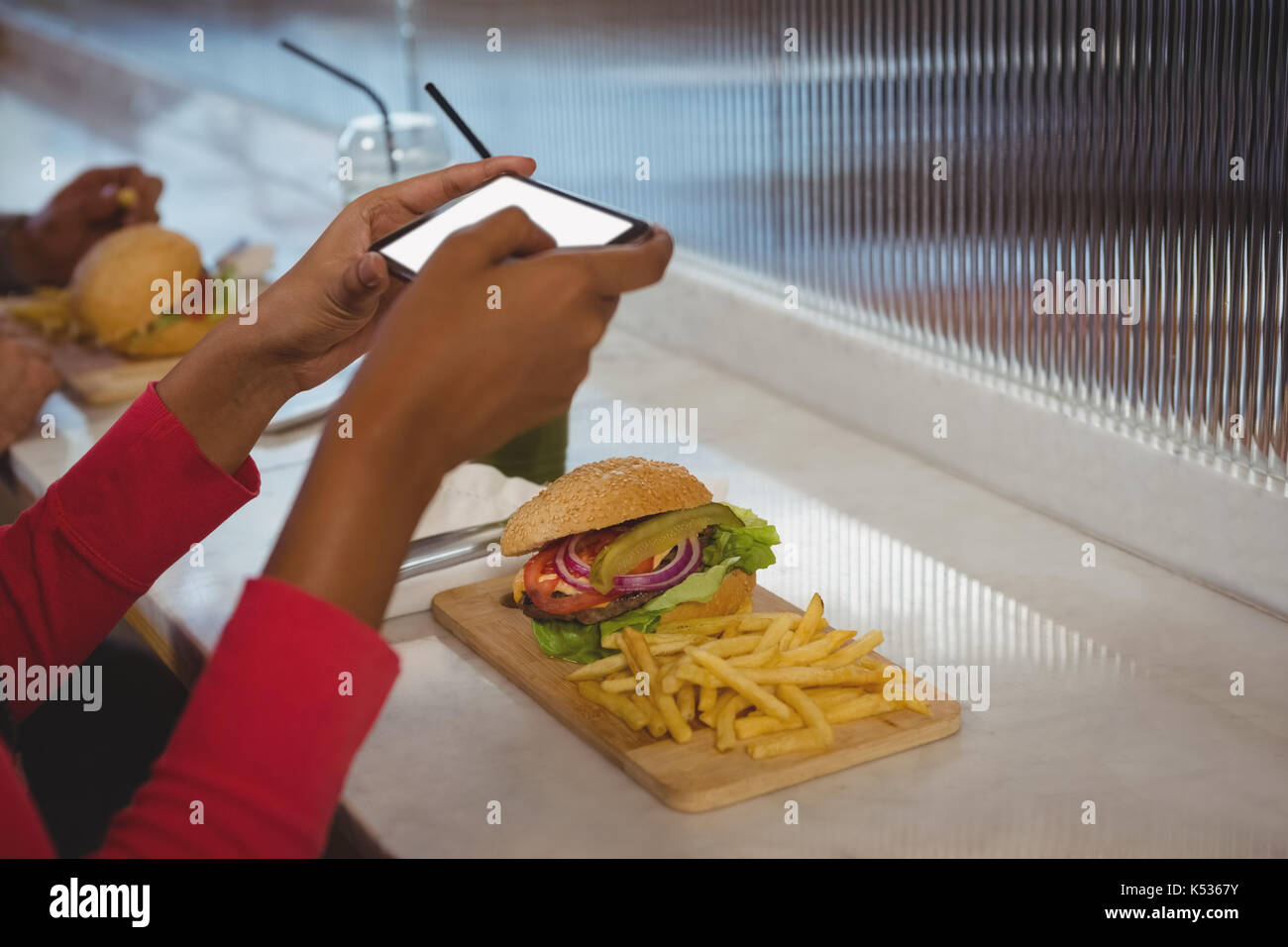 Mains de femme cultivée en photographiant les frites et burger at counter in cafe Banque D'Images