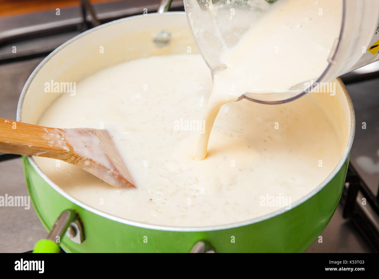 Riz au lait avec cannelle et raisins secs Préparation : l'ajout de lait en poudre pour le riz cuit Banque D'Images