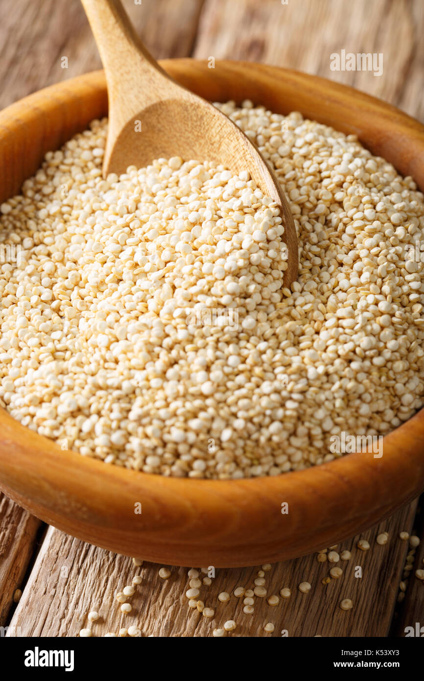 Les matières premières organiques quinoa blanc close-up dans un bol en bois sur la table verticale. Banque D'Images