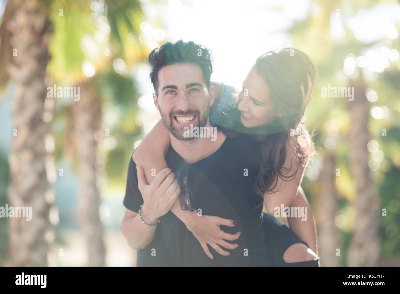 Portrait of happy young man giving his girlfriend un piggy back ride Banque D'Images