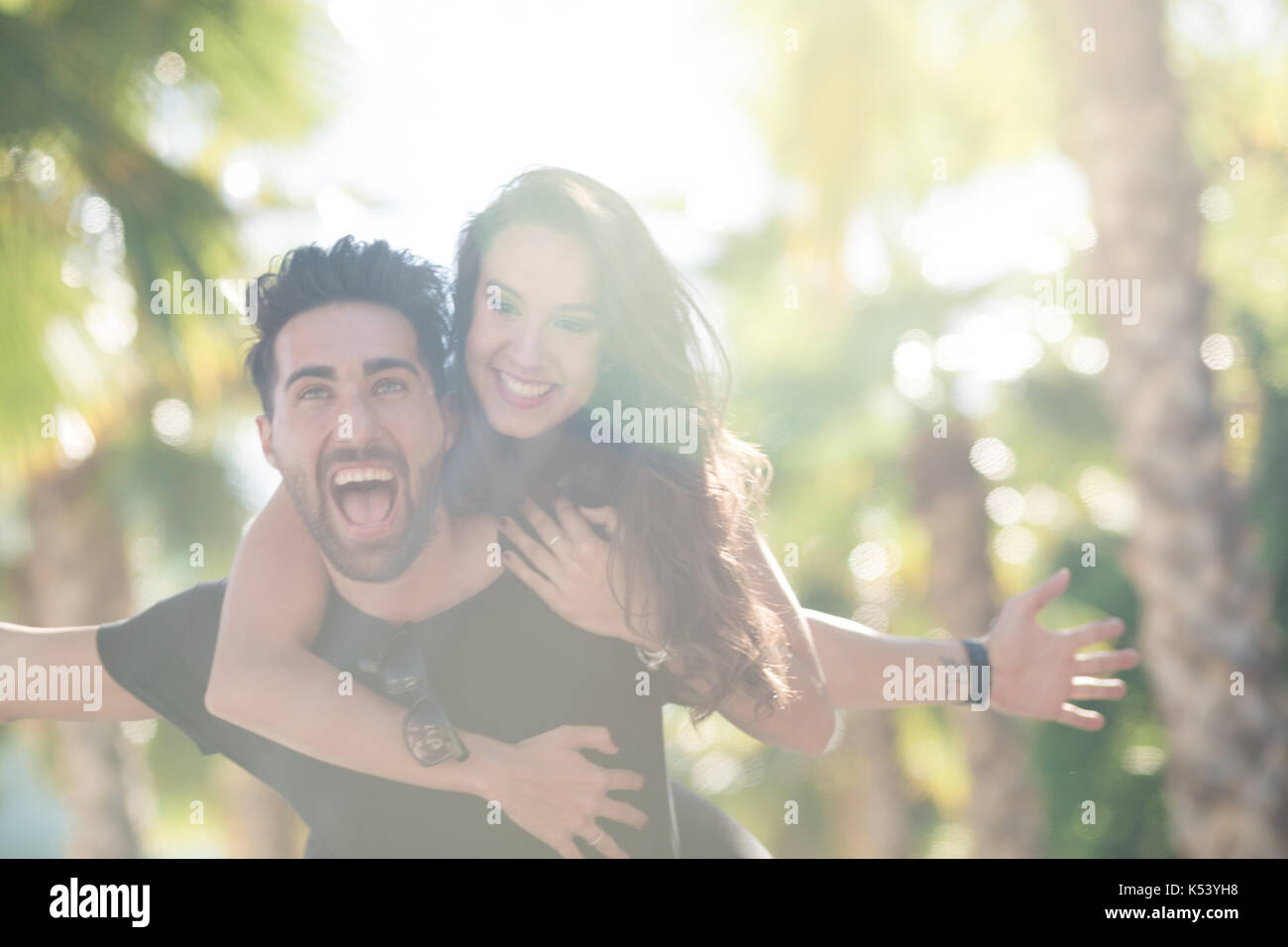 Portrait d'homme heureux avec sa petite amie donnant armes propagation un piggy back ride Banque D'Images