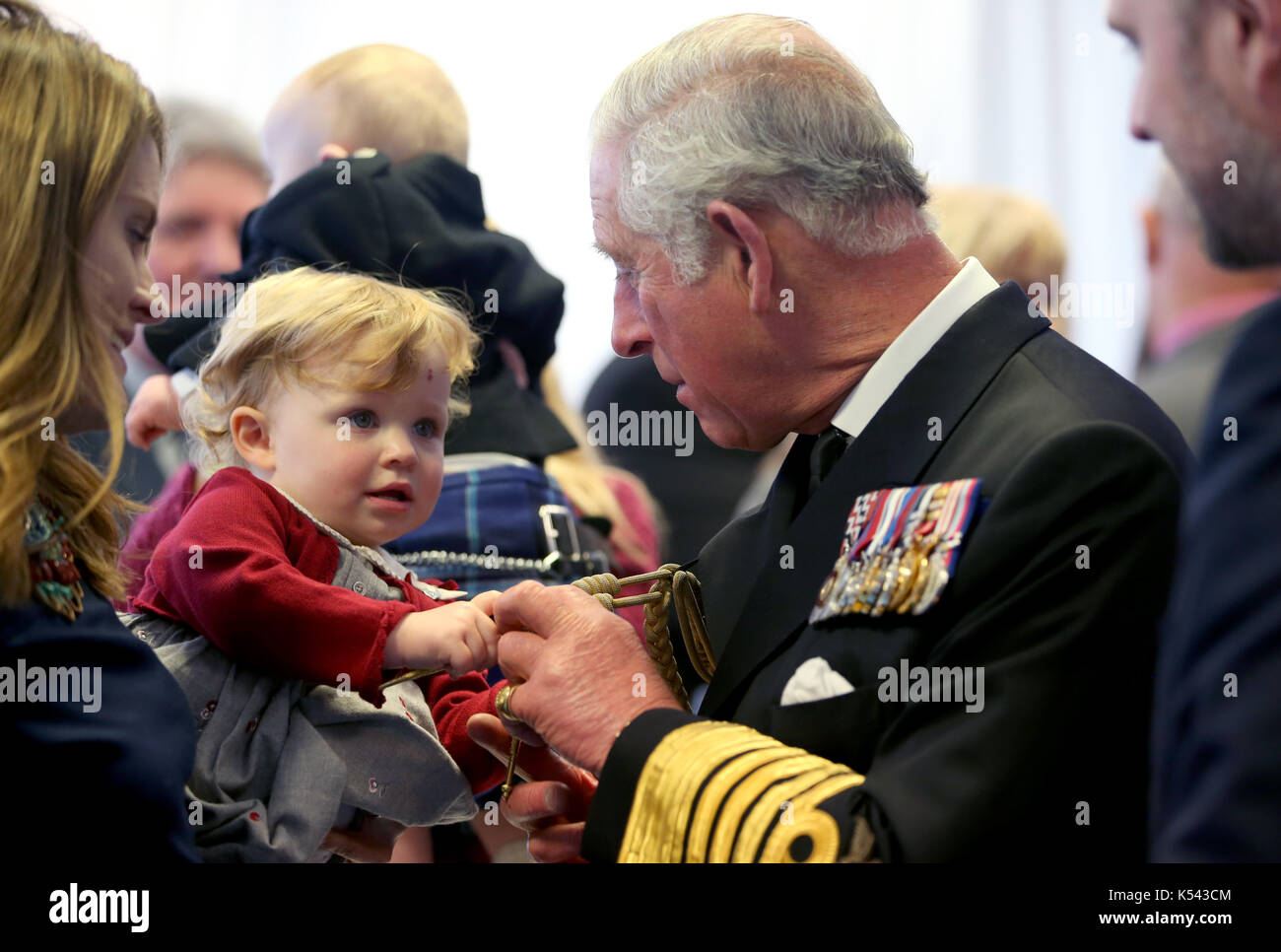 18 mois imogen holm tire sur la tresse sur l'uniforme du prince de Galles, connu sous le nom de duc de Rothesay tandis qu'en Ecosse, lors d'une réception qui a suivi la cérémonie de baptême du porte-avions HMS Prince de Galles à l'arsenal royal à Rosyth. Banque D'Images