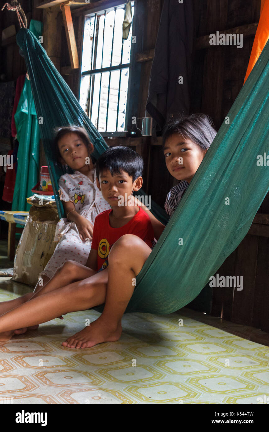 Sihanoukville, Cambodge - 7/20/2015 : trois enfants sont assis dans un hamac à l'intérieur de leur maison dans un village de pêche en milieu rural. Banque D'Images