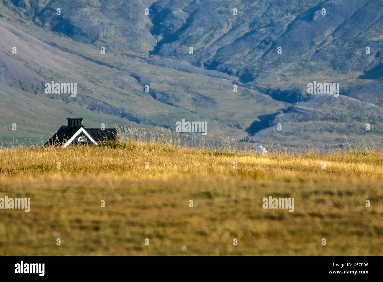 Paysage montagneux avec une maison rurale visible au-dessus du champ en premier plan. Banque D'Images